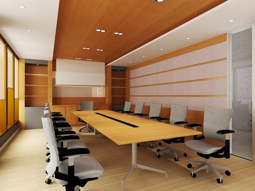 Modern conference room with a long wooden table, ergonomic chairs, wood panel walls, and recessed ceiling lighting.