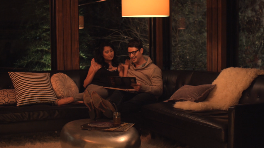 two people sitting on a couch looking at a tablet in a warm, dimly lit living room