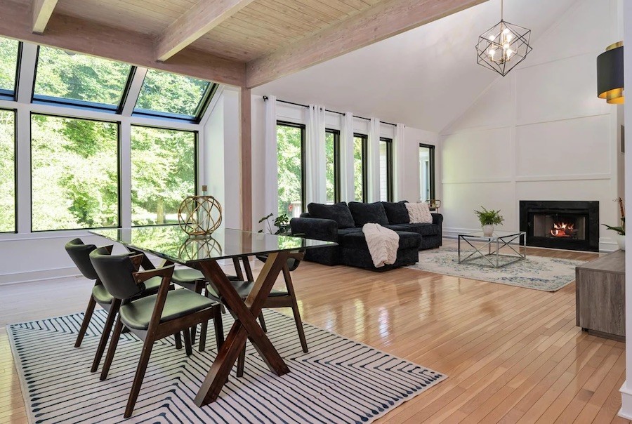 open-concept dining room, living room combination with expansive windows overlooking trees