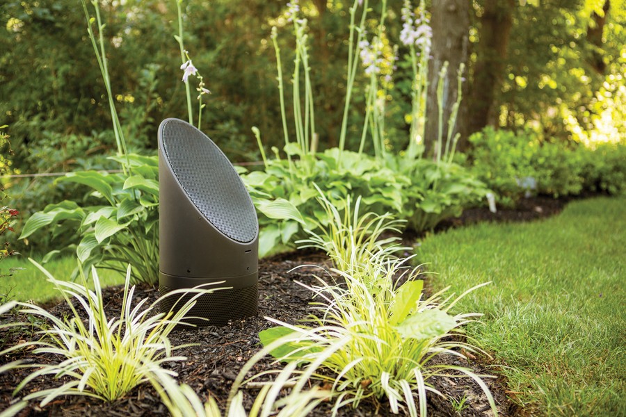 An outdoor speaker discreetly embedded within a green landscape.