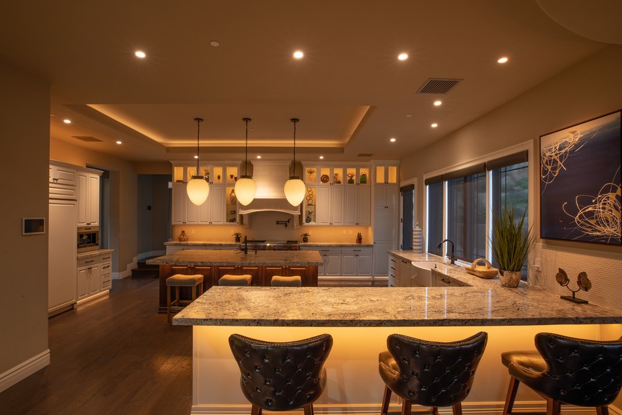 A kitchen warmly illuminated by Control4 Vibrant Linear lighting, with a Control4 touchscreen on the wall.